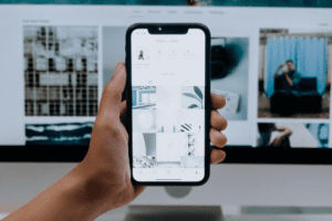 L'immagine rappresenta un iPhone tenuto frontalmente in mano con una schermata che presenta dei social